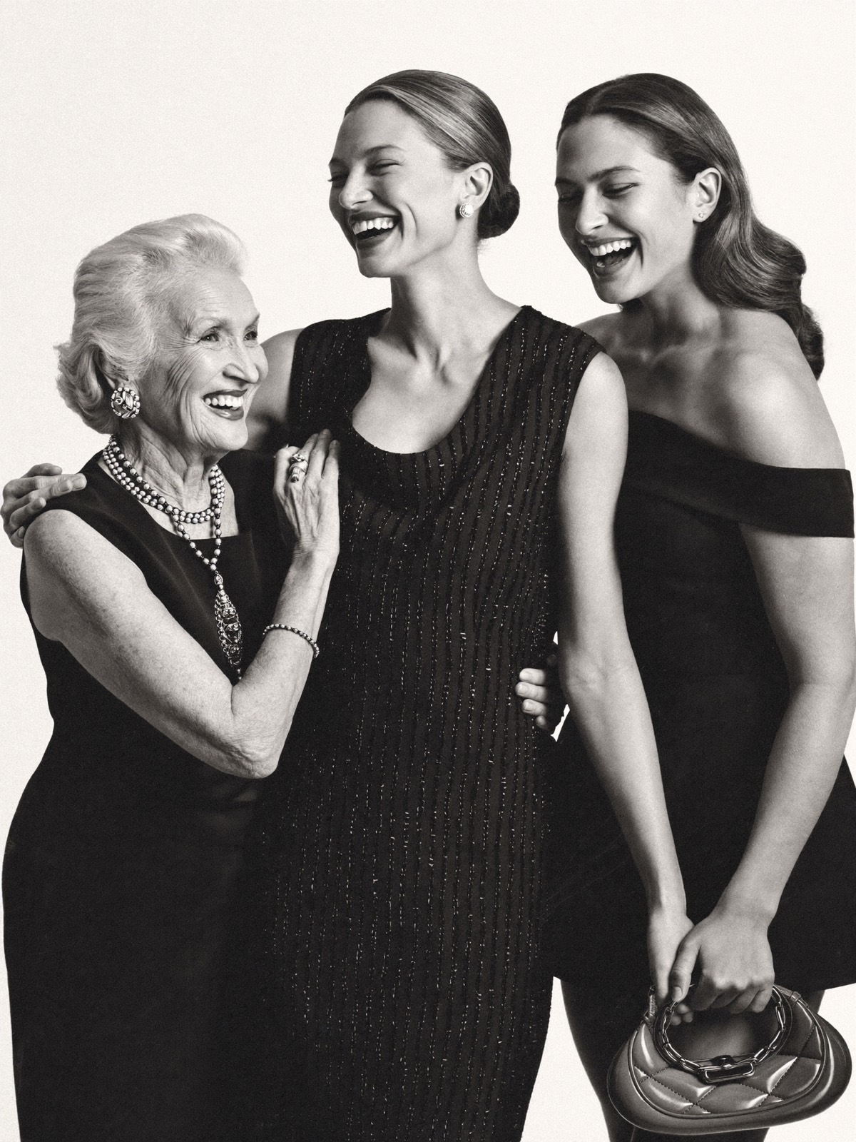 Grandmother, mother, and daughter laughing together arm in arm