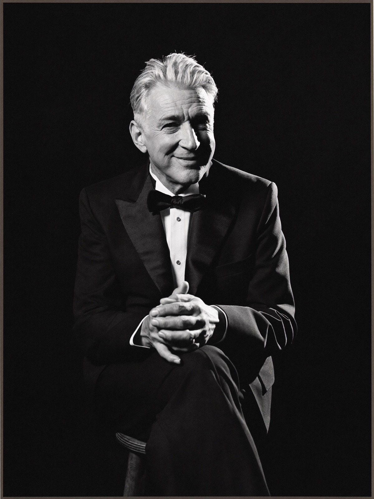 Distinguished gentleman in a tuxedo photographed against a black backdrop