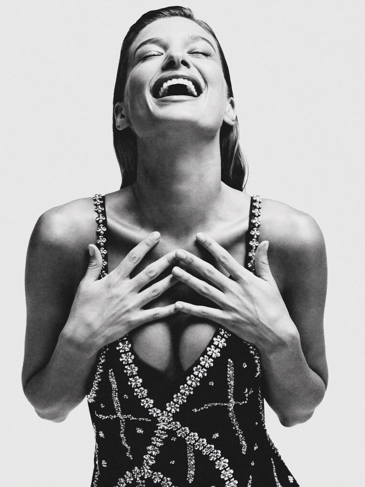 Woman in a beaded dress laughing with her head tilted back