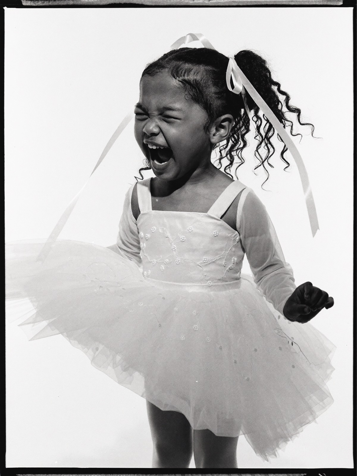 Young flower girl in a tulle dress mid-twirl, giggling